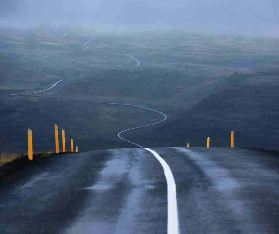 A winding road over hills on a foggy day
