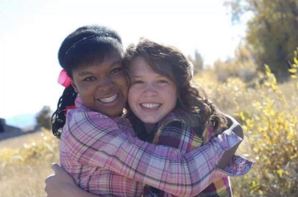 A photo of Lily and her foster sister embracing in a field. Depicts a part of foster care story.
