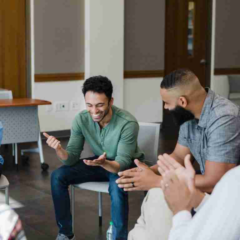 A group of people sitting in a circle laughing and listening to shared stories.
