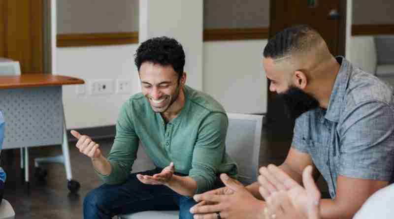 A group of people sitting in a circle laughing and listening to shared stories.
