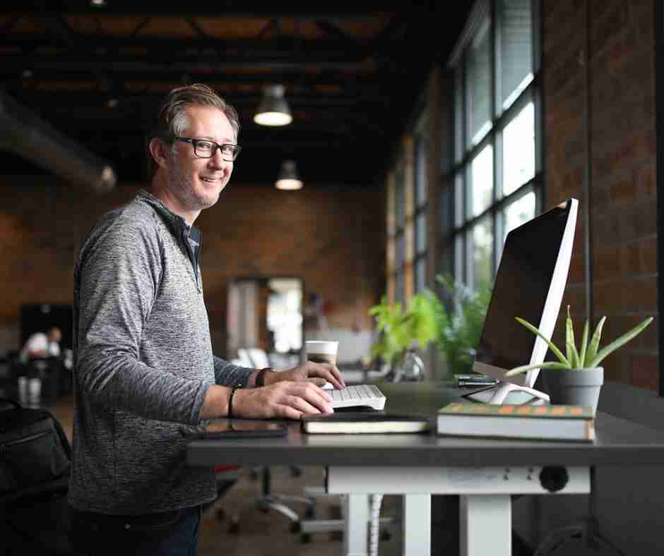 Photo of man standing at desk smiling