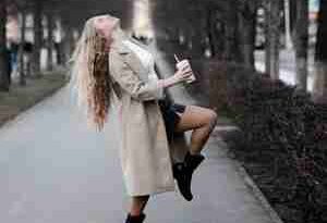 A woman dancing in the street with a cup of coffee in her hand. She is celebrating the no career life and rejecting family expectations.