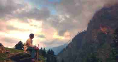 Man sitting on a mountainside looking at a clouds covering the adjacent mountain. Photo by Arijit Chakraborty from Pixabay