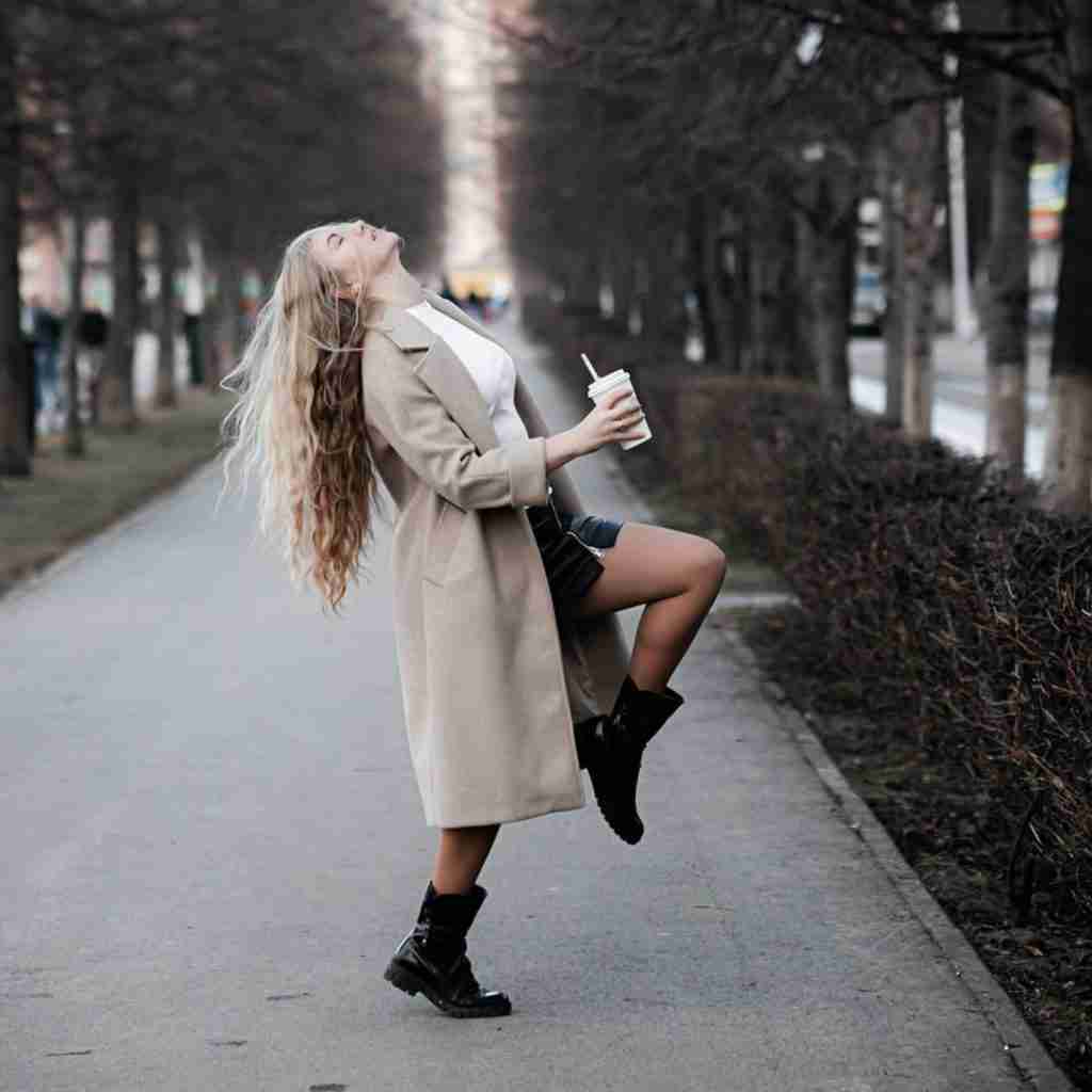 Woman dancing in park with coffee in her hand