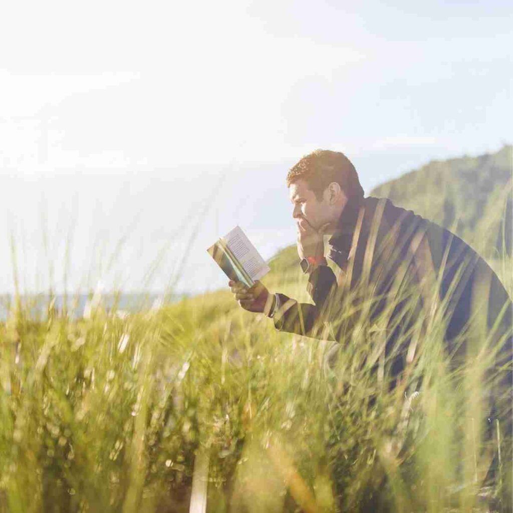 Image of man on a bench reading a book in tall wavy grass by Pexels from Pixabay