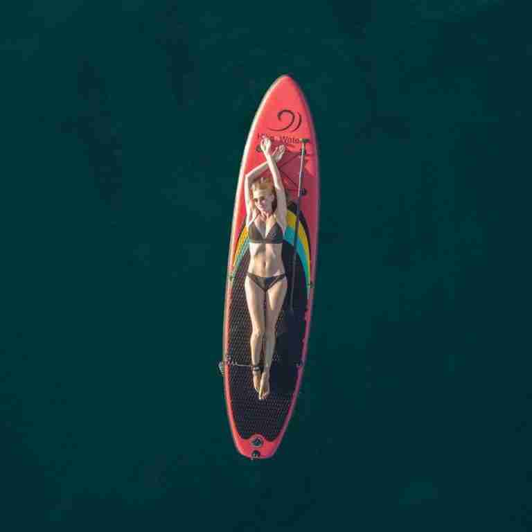 Girl laying on paddle board in middle of ocean. Image by Alexey Komissarov from Pixabay