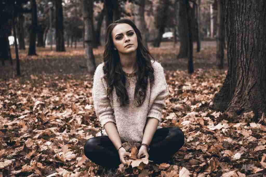 Orphaned girl sitting in leaves, depicting strength and resilience 