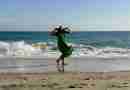 Woman in green dress on beach with hat wind blowing hair and dress. Image by Myléne from Pixabay