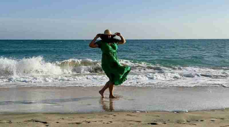 Woman in green dress on beach with hat wind blowing hair and dress. Image by Myléne from Pixabay