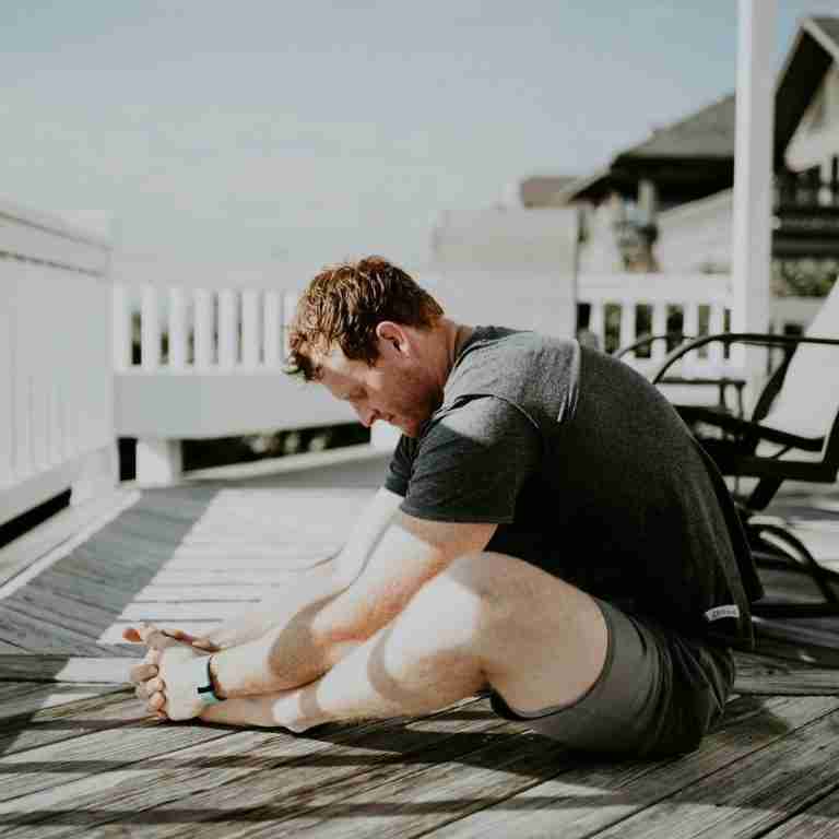 Man doing yoga on porch in sunlight. Photo by Scott Broome on Unsplash