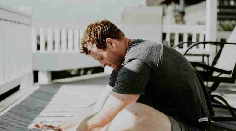 Man doing yoga on porch in sunlight. Photo by Scott Broome on Unsplash