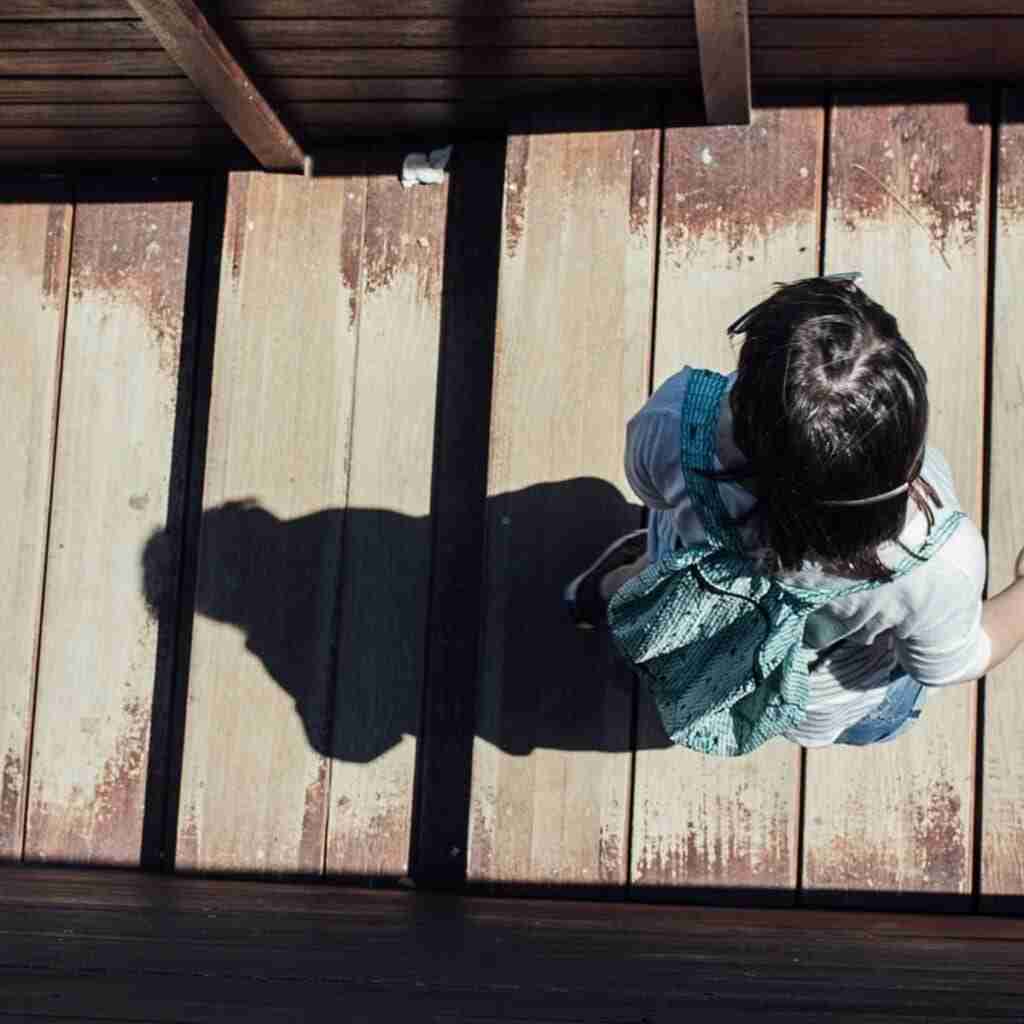 keepgoingfeatured (1) - Resilient Stories Aerial shot of girl walking along dock, shadow cast behind her.