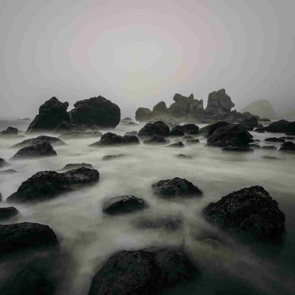 keepgoingfeatured (3) - Resilient Stories Rocks jutting out of the water on foggy, cloudy day.
