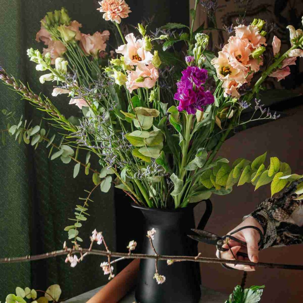 Hand with scissors cutting, flower arranging in a vase. Photo by micheile henderson on Unsplash