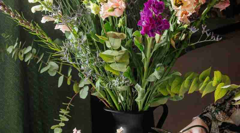 Hand with scissors cutting, flower arranging in a vase. Photo by micheile henderson on Unsplash