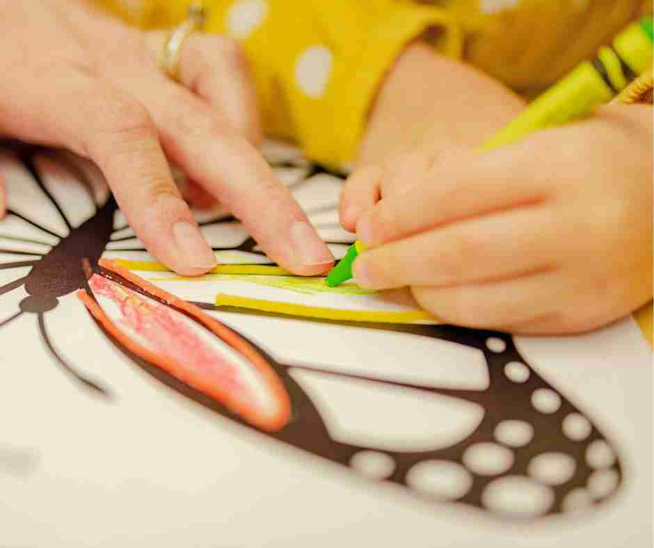 Untitled design (60) - Resilient Stories Photo of child and adult hands coloring a butterfly together with crayons