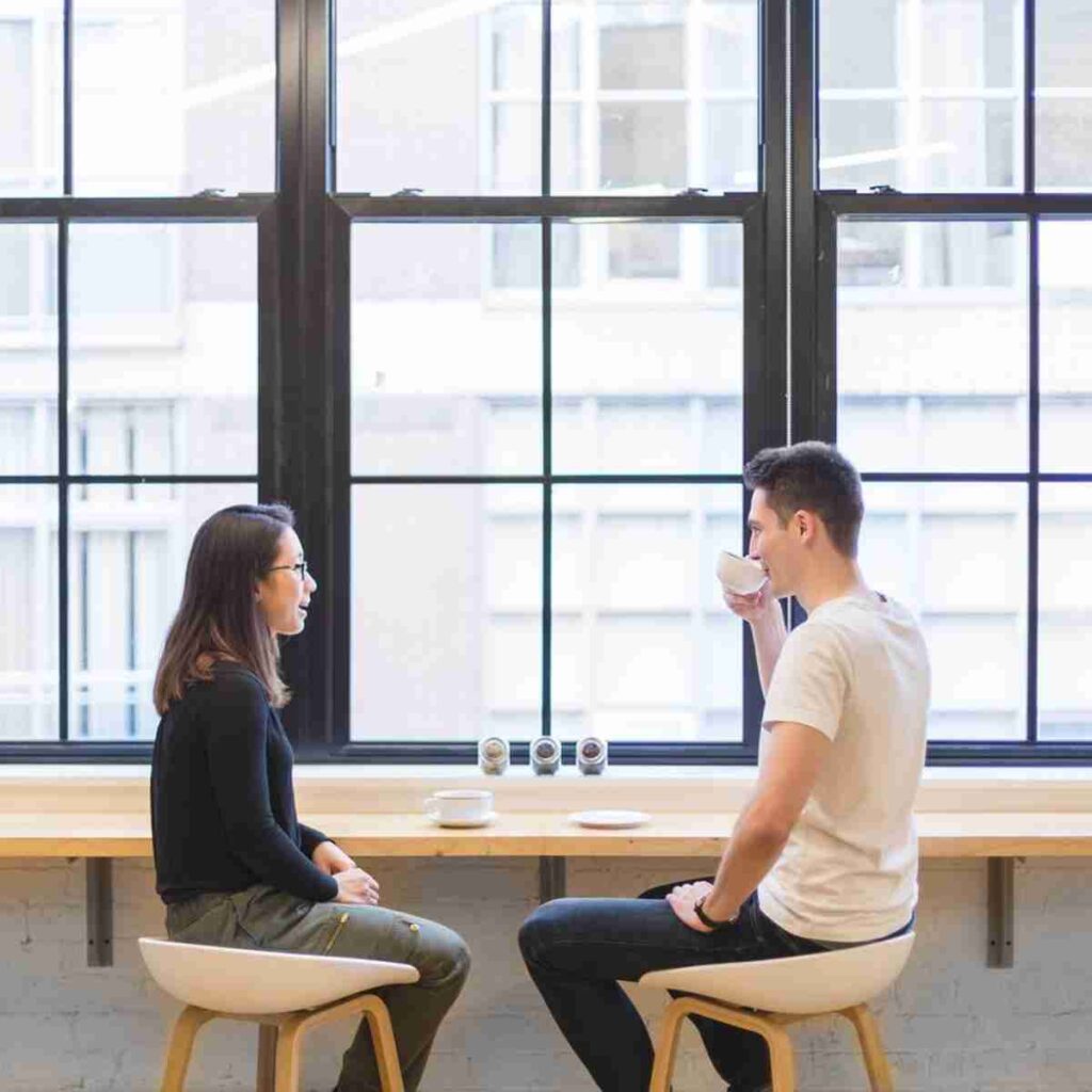 Asian man and woman sitting in from of large window enjoying a conversation over tea/coffee. Image by StockSnap from Pixabay