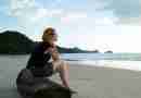 Photo of woman sitting on log on a beach looking pensive. Image by Engin Akyurt from Pixabay