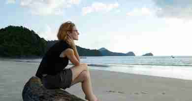 Photo of woman sitting on log on a beach looking pensive. Image by Engin Akyurt from Pixabay