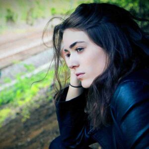 Photo of girl sitting outside looking sad and pensive. Photo by Kyle Broad on Unsplash