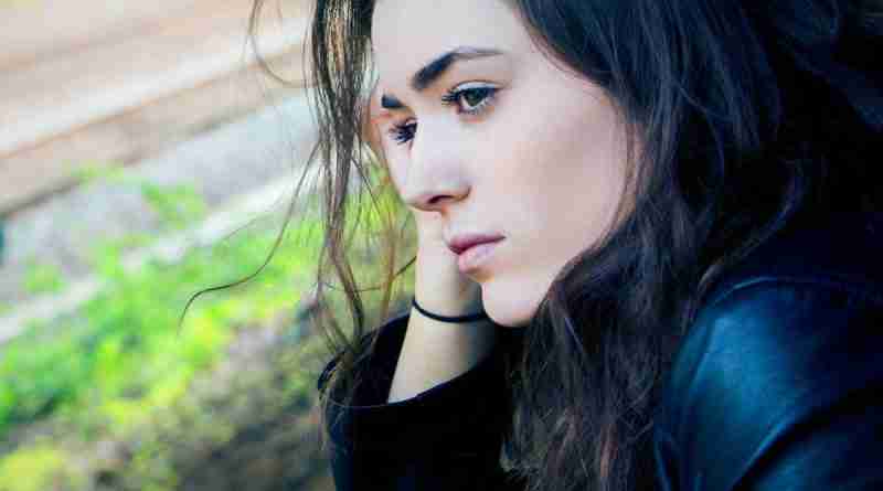 Photo of girl sitting outside looking sad and pensive. Photo by Kyle Broad on Unsplash