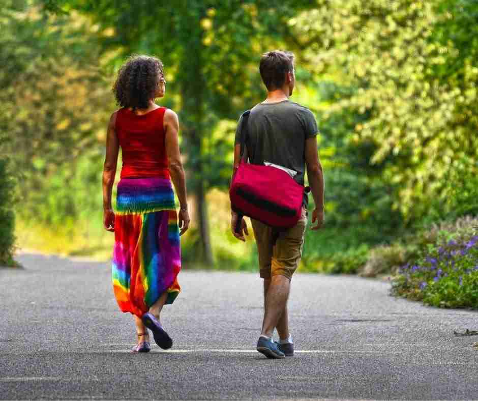 Couple walking along a park path, not touching each other.