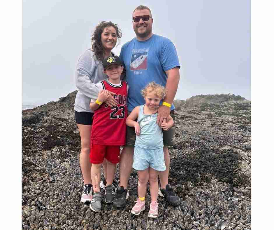 Photo of family by the ocean; mom, dad, son, and daughter.