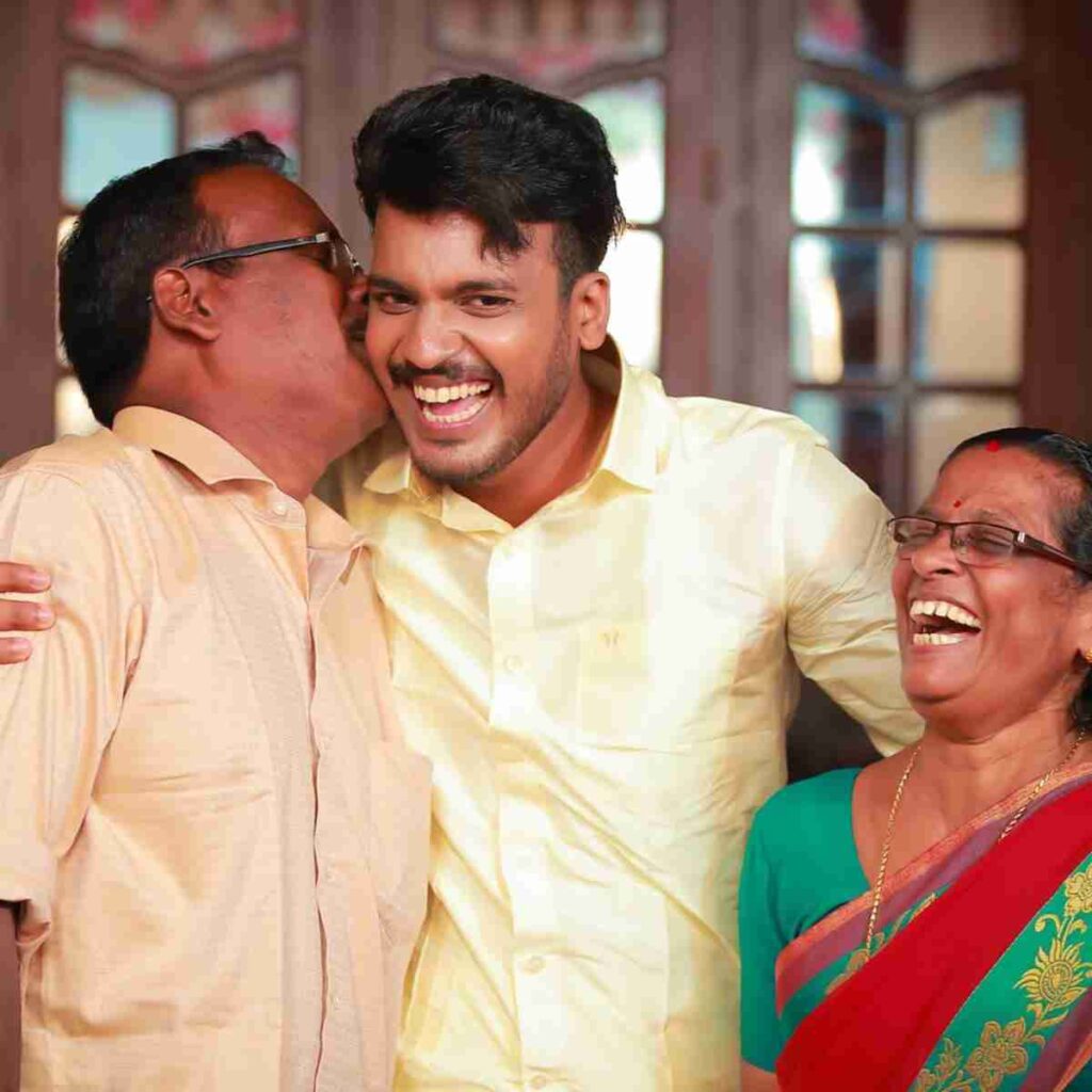 Image of Indian parents embracing son with big smiles and hugs. Image by ANOOP VS from Pixabay