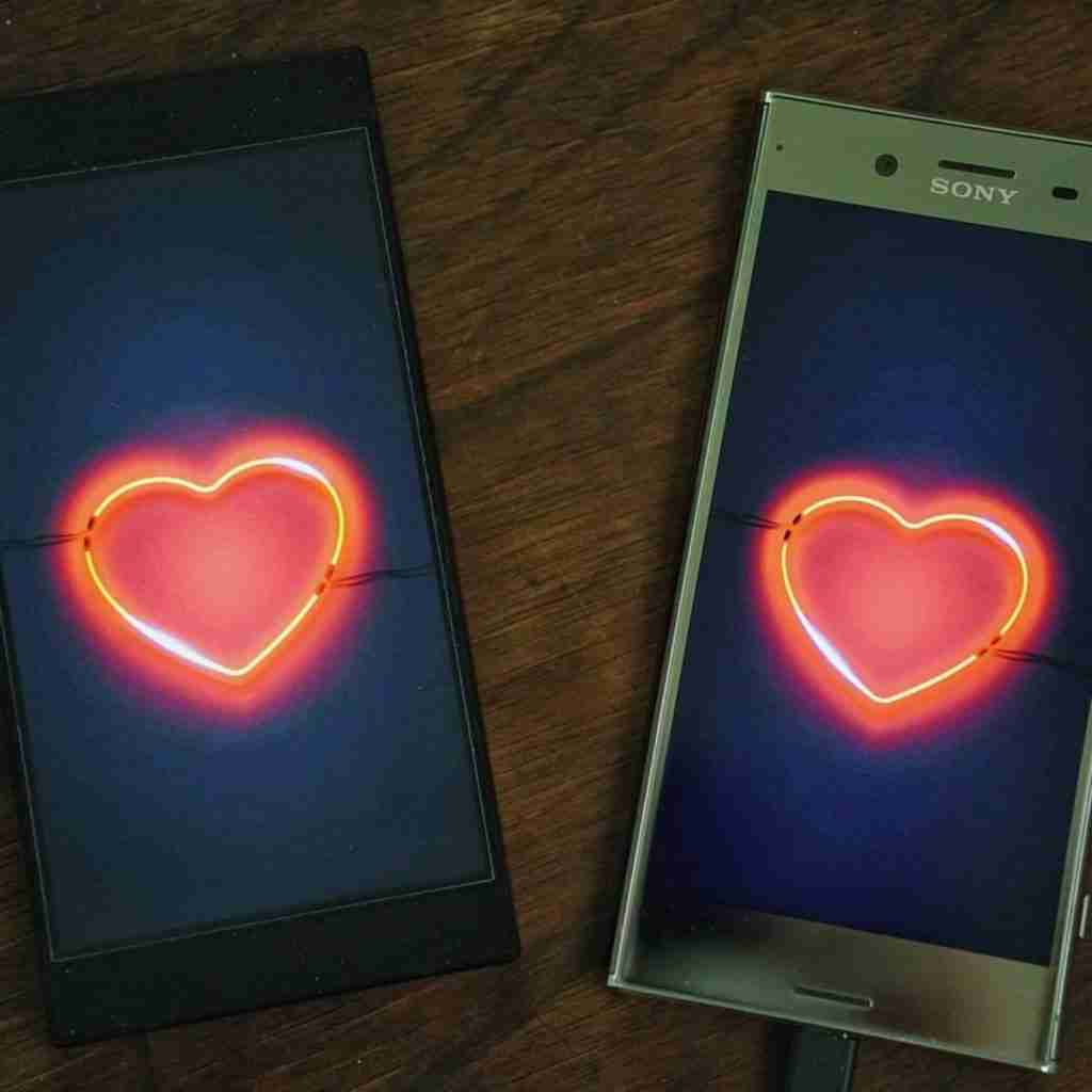 Photo of two cell phones showing glowing hearts on the screen to depict online dating