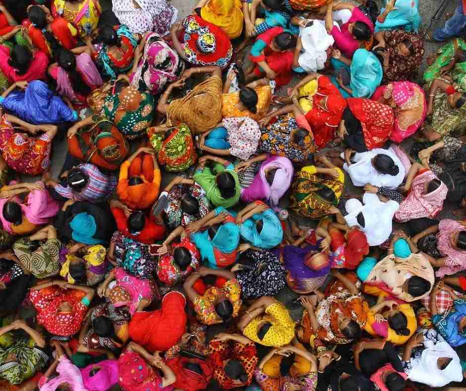Photo of a crowd of women all sitting together, each one dressed in brightly colored garments depicting authenticity and be true to yourself.