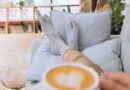 Person relaxing on couch with socks on drinking cappuccino with heart foam art