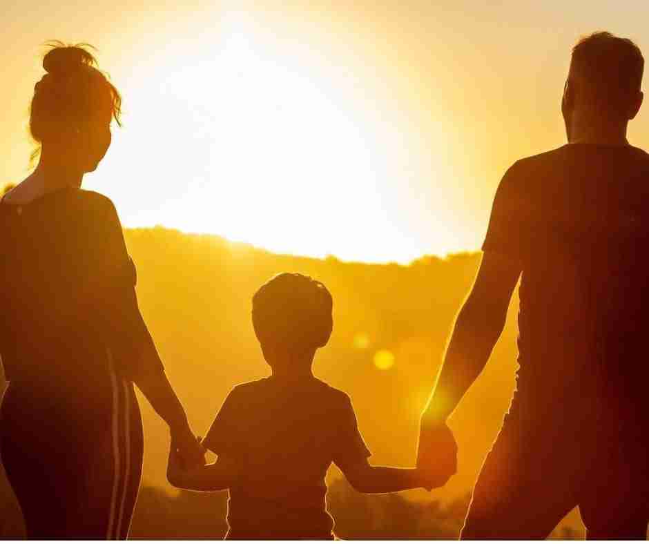 Family (man, woman, child) holding hands and watching the sunset