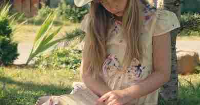 A young girl sits in the grass reading a book demonstrating bibliotherapy.