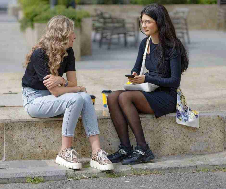 Two women sitting in public picnic area talking.