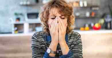 A woman sitting at a table with her face in her hands and her eyes closed, demonstrating what it feels like to be with someone who is emotionally unavailable.