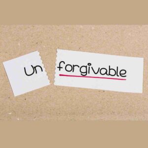 The word "unforgivable" is written on a slip of paper with the word un torn off. Choosing to forgive or not forgive someone is a personal choice.