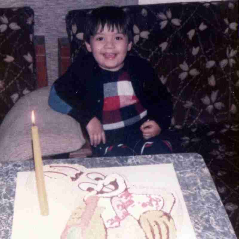 A photo of Mehmet as a child in front of a Bugs Bunny cake.