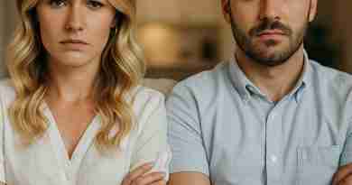 A young couple sits closely on a couch with arms crossed and serious expressions, facing forward. Both wear casual clothing—white tops and jeans—and appear to be in a moment of tension or disagreement, suggesting a relationship conflict or emotional distance.