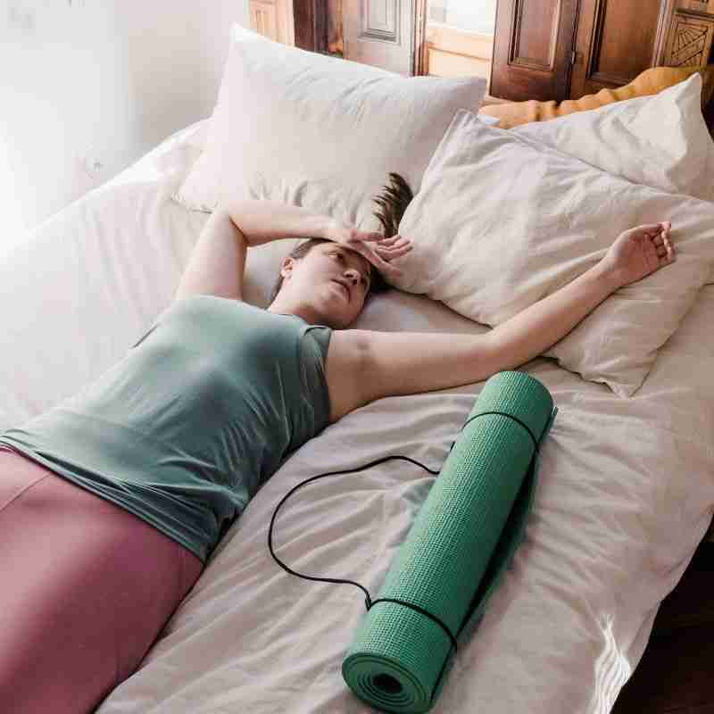 A woman lies on her bed exhausted after her workout.