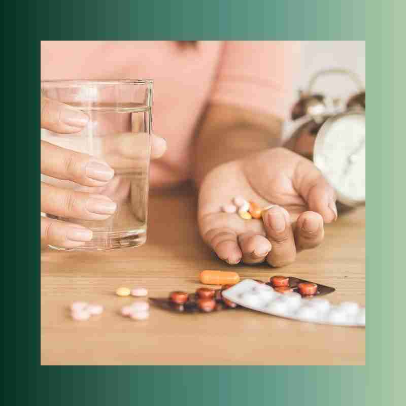 An image of a woman taking a handful of different medications.