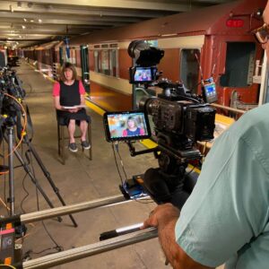 A photo of Bernie being interviewed after transitioning from the male voice behind the NYC subway.