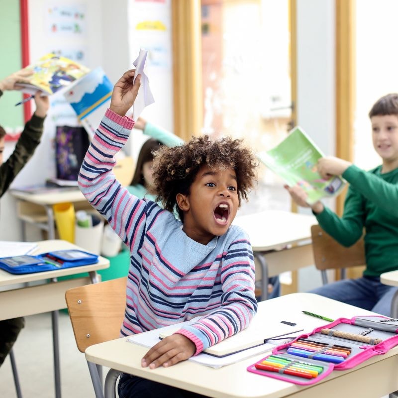 A group of young kids shouting in a classroom.