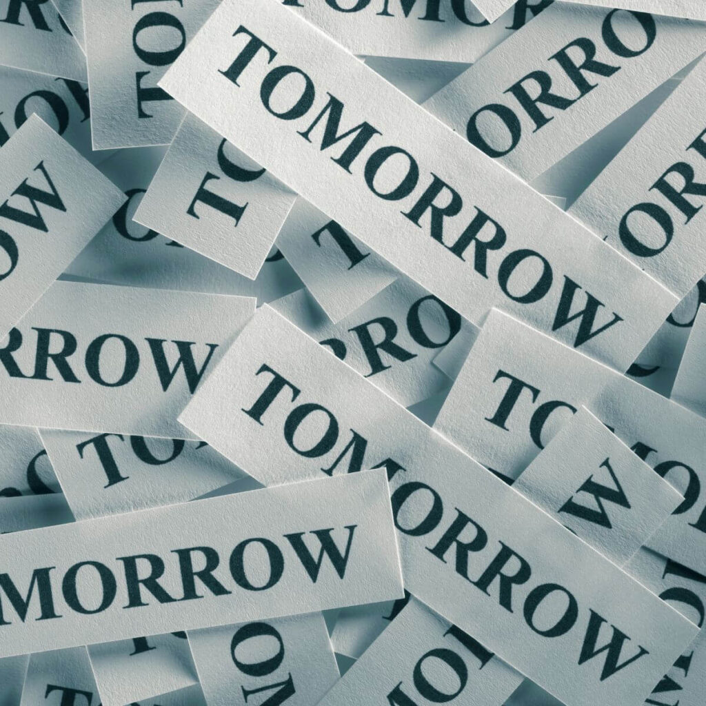 Tiny slips of paper with the word tomorrow printed on them and piled together.