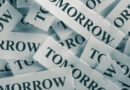 Tiny slips of paper with the word tomorrow printed on them and piled together.