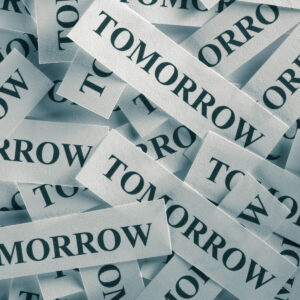 Tiny slips of paper with the word tomorrow printed on them and piled together.