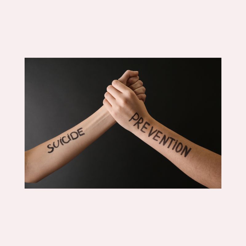Two hands clasped as if they were wrestling. One has the word suicide written on it, the other has prevention.