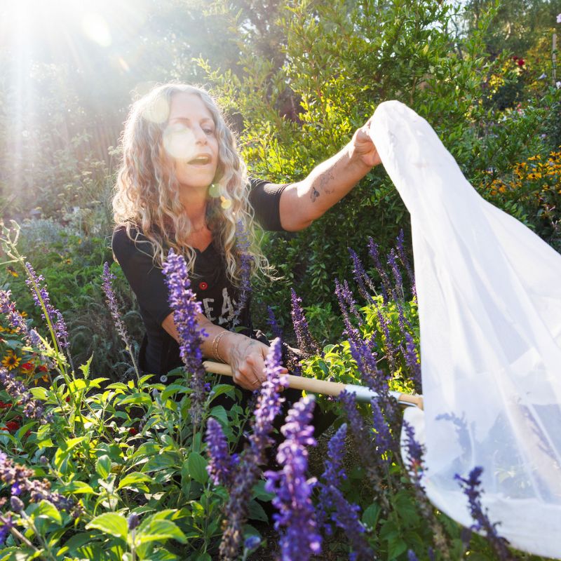A photo of Dina in her garden with a butterfly net.